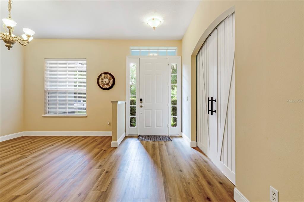A single-story house with a red front door sits on a grassy lot with trees — 1085 TAYLOR ROAD E, DELAND, FL