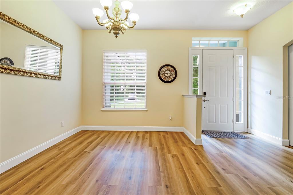 An entryway features wood-look flooring, a white front door with sidelights, and sliding barn doors — 1085 TAYLOR ROAD E, DELAND, FL