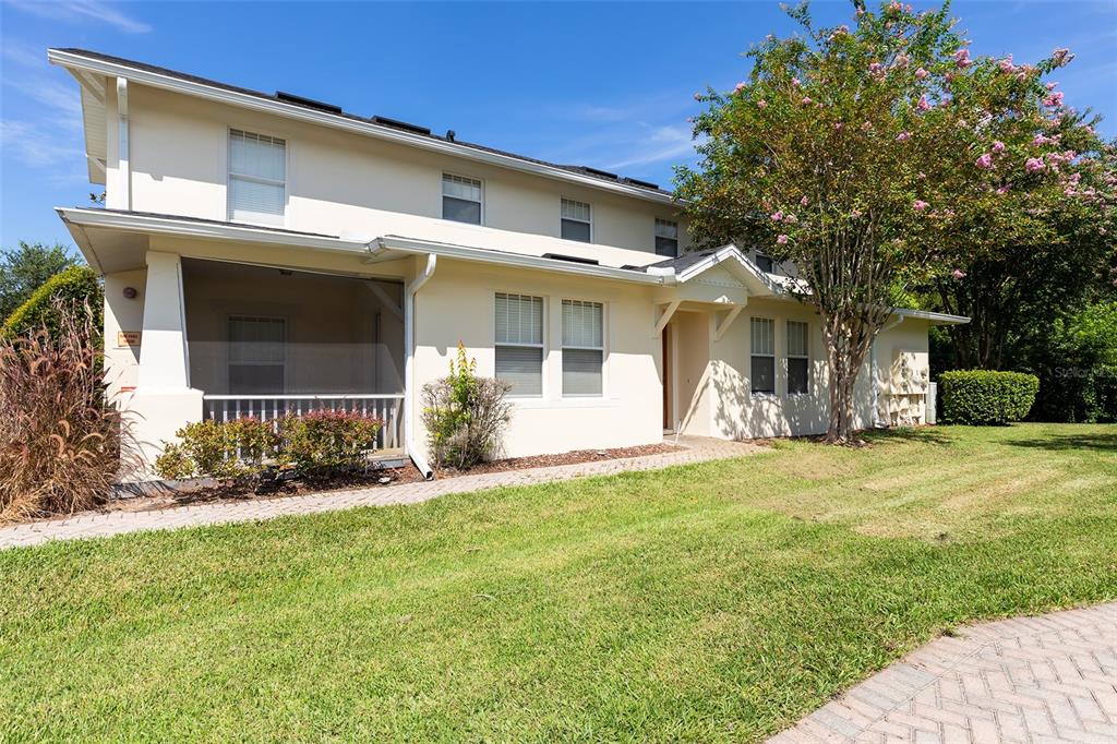 A two-story beige building with a screened-in porch and a paved walkway on a lawn — 9866 TIVOLI VILLA DRIVE, ORLANDO, FL