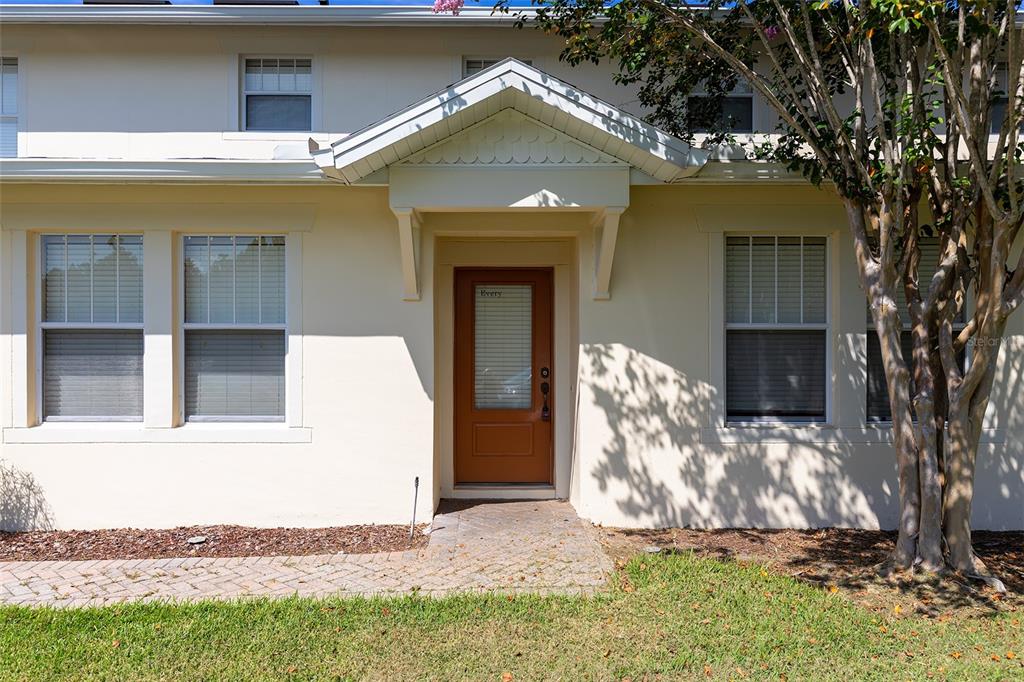 A tan exterior wall features a brown front door under a small gabled porch roof — 9866 TIVOLI VILLA DRIVE, ORLANDO, FL