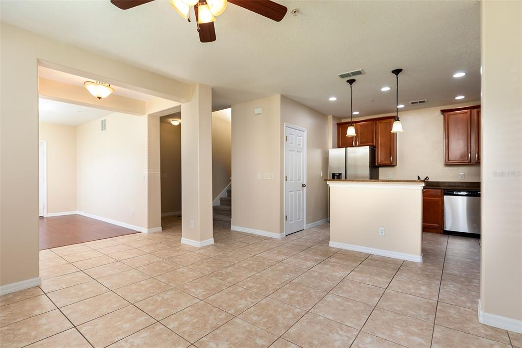 An open-concept kitchen and living area features tile flooring, wood cabinets, and stainless steel appliances — 9866 TIVOLI VILLA DRIVE, ORLANDO, FL