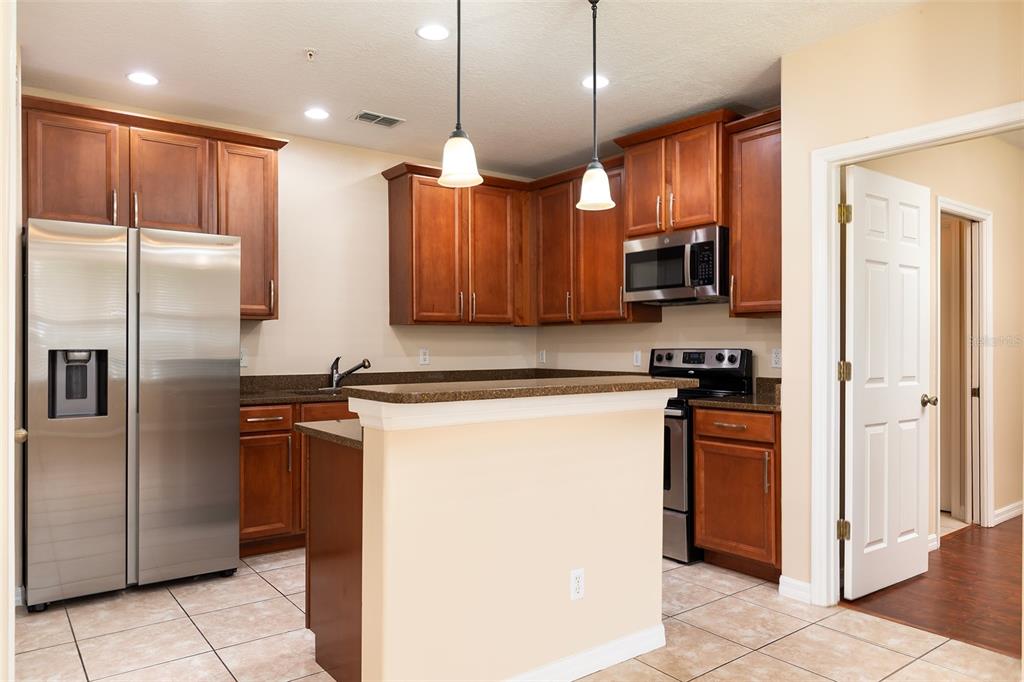A kitchen with wood cabinets, stainless steel appliances, a breakfast bar, and tile flooring — 9866 TIVOLI VILLA DRIVE, ORLANDO, FL