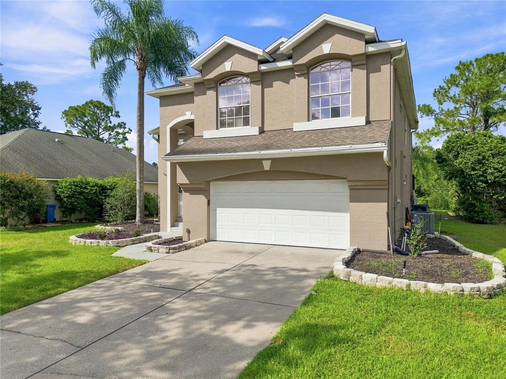 A two-story house with a beige stucco exterior, a two-car garage, and a palm tree — 7326 YARDLEY WAY, TAMPA, FL