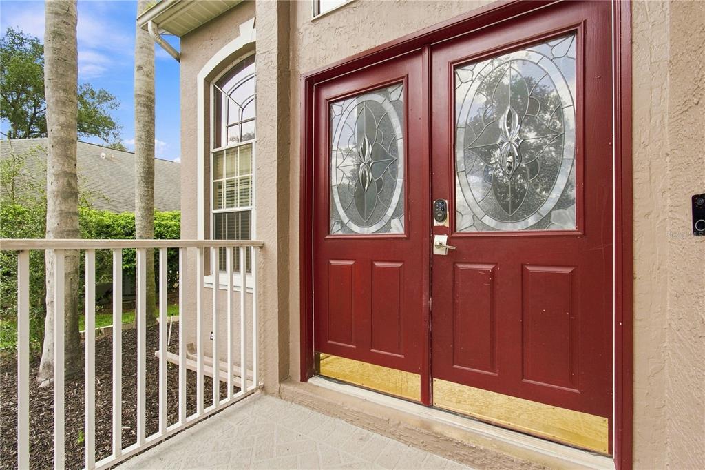 A red double front door with decorative glass inserts sits on a covered porch — 7326 YARDLEY WAY, TAMPA, FL