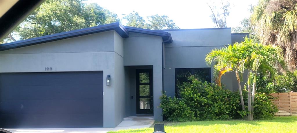 A modern, single-story gray house with a flat roof, a garage, and a front entrance — OLD TRAIL DRIVE, NOKOMIS, FL