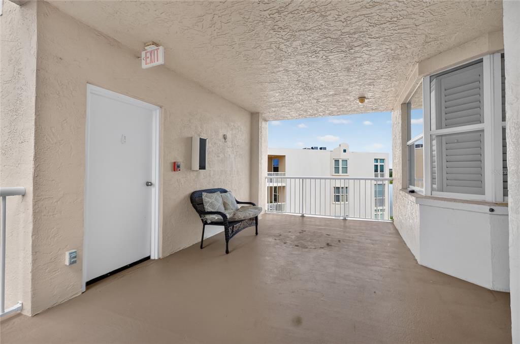 A covered balcony features a white door, a wicker bench, and a metal railing — 6251 SHORELINE DRIVE UNIT 2301, SEMINOLE, FL