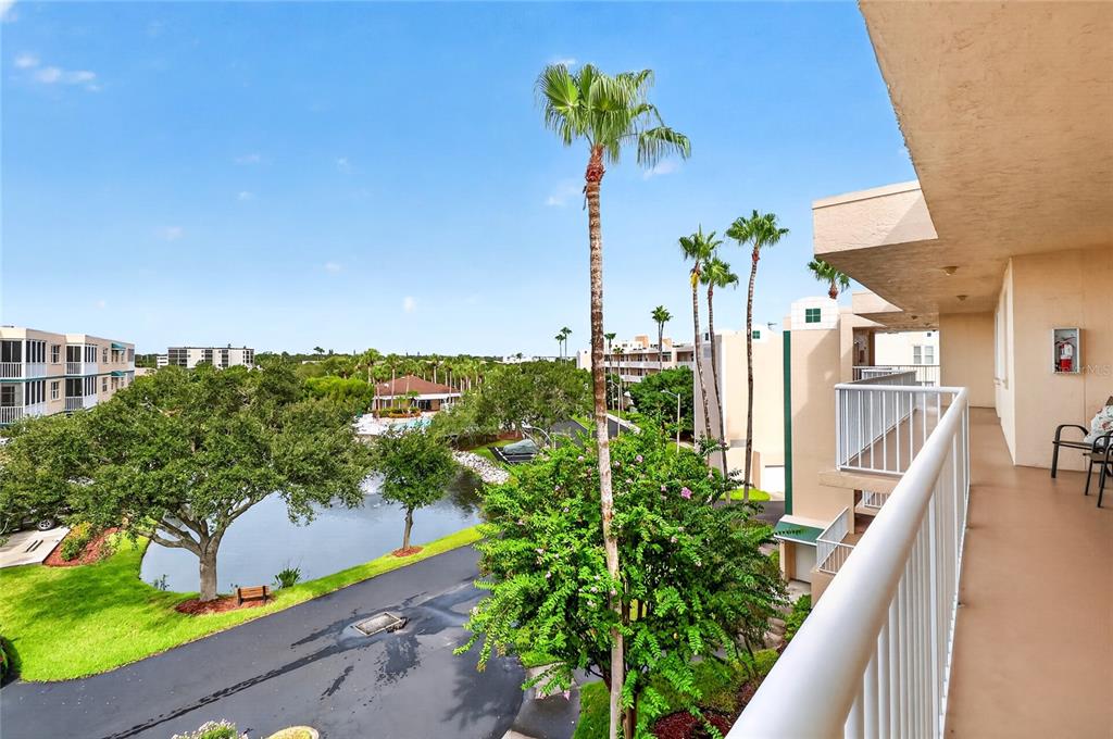 A view from a balcony overlooking a pond, palm trees, and surrounding apartment buildings — 6251 SHORELINE DRIVE UNIT 2301, SEMINOLE, FL