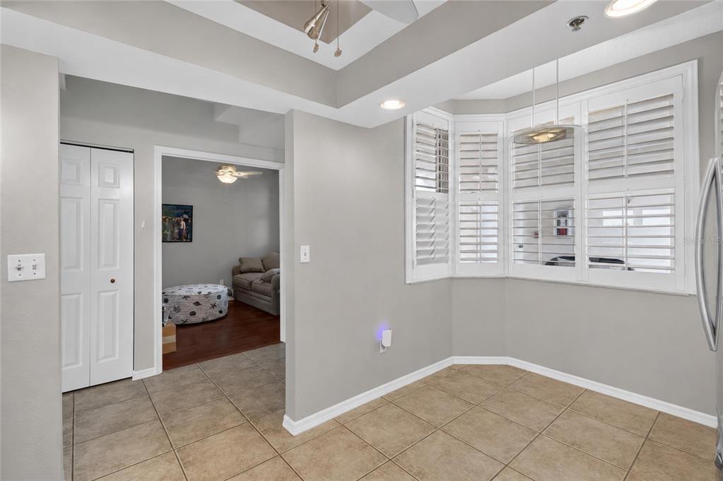 A dining area with tile floors, a bay window with shutters, and an adjacent living room — 6251 SHORELINE DRIVE UNIT 2301, SEMINOLE, FL