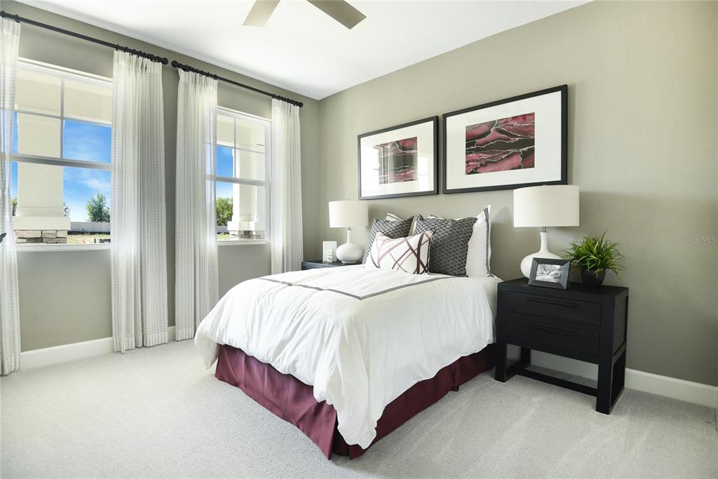 A bedroom features a bed with a white comforter, dark bed skirt, and two framed prints — 1261 DAISY HILL AVENUE, DUNDEE, FL