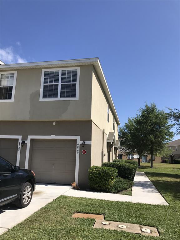 A two-story townhouse exterior features a garage, a driveway, and a patch of discolored stucco — 4020 PEMBERLY PINES CIRCLE, ST CLOUD, FL