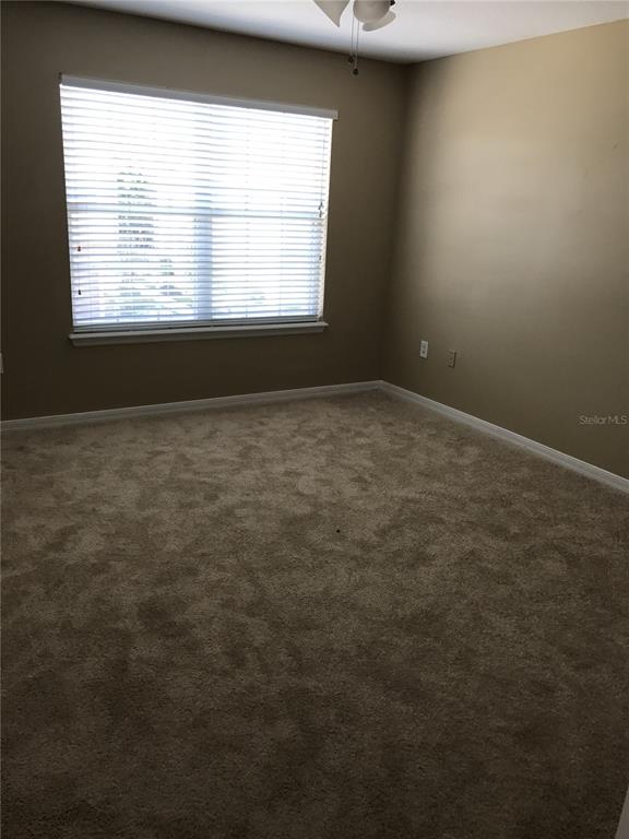 An empty bedroom features beige walls, tan carpeting, and a window with white horizontal blinds — 4020 PEMBERLY PINES CIRCLE, ST CLOUD, FL