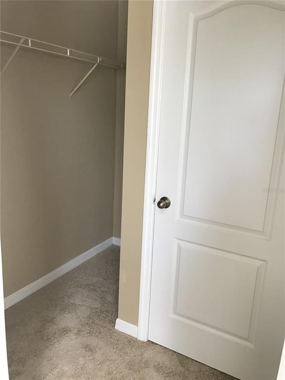 A walk-in closet with beige carpet and a white door with a brass knob — 4020 PEMBERLY PINES CIRCLE, ST CLOUD, FL