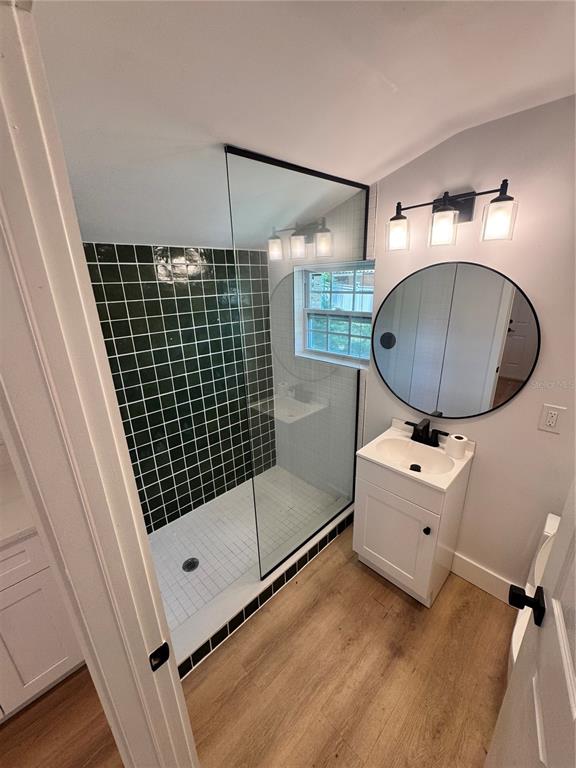 A bathroom features a walk-in shower with dark green tiles, a white vanity, and a mirror — 309 E WOODWARD AVENUE, EUSTIS, FL