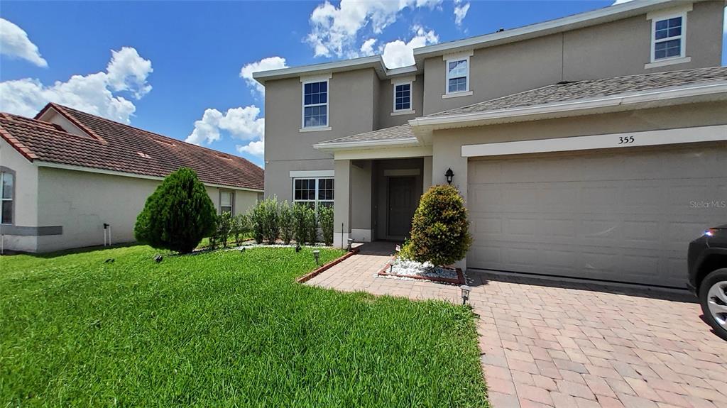 A two-story suburban house with a beige stucco exterior, a two-car garage, and a driveway — 355 GRANADA BOULEVARD, DAVENPORT, FL