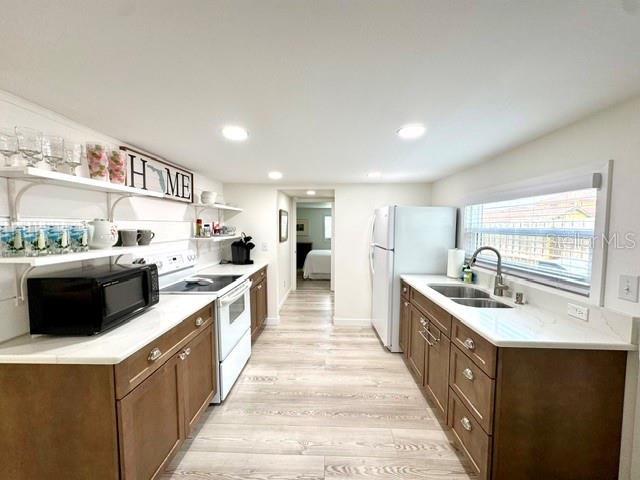 A kitchen features wood cabinets, white countertops, stainless steel appliances, and light wood-look flooring — 1357 LAKESHORE DRIVE, MOUNT DORA, FL
