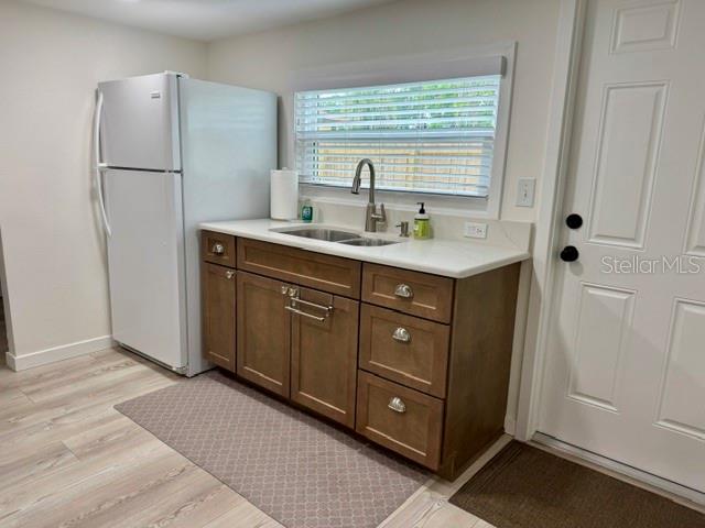 A kitchen area features a white refrigerator, wood cabinets, a sink, and a white door — 1357 LAKESHORE DRIVE, MOUNT DORA, FL