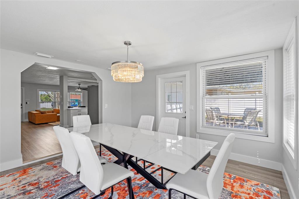 A dining room features a white marble-topped table, six white chairs, and a crystal chandelier — 2003 6TH PLACE SW, LARGO, FL