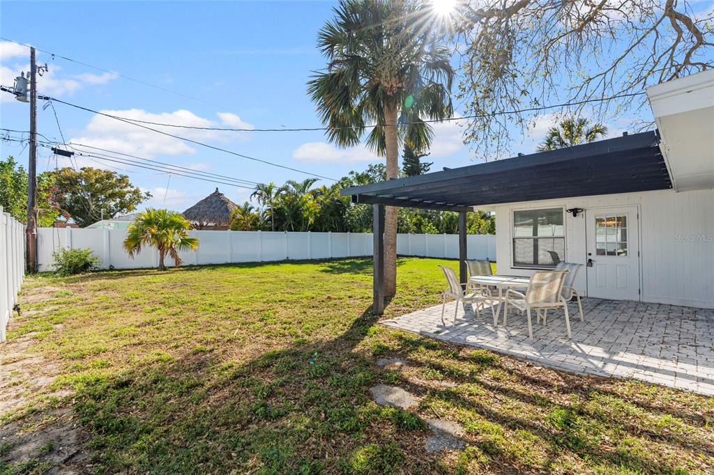 A backyard features a paved patio with a pergola, outdoor furniture, and a white fence — 2003 6TH PLACE SW, LARGO, FL