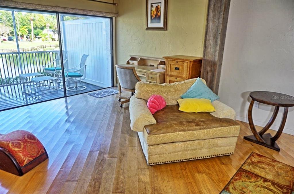 A living room features hardwood floors, a large armchair, a desk, and a sliding glass door — 1859 MAZO MANOR UNIT U6, LUTZ, FL