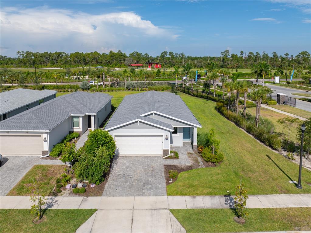 An aerial view shows a single-story gray house with a two-car garage and paved driveway — 44125 FRONTIER DRIVE, PUNTA GORDA, FL