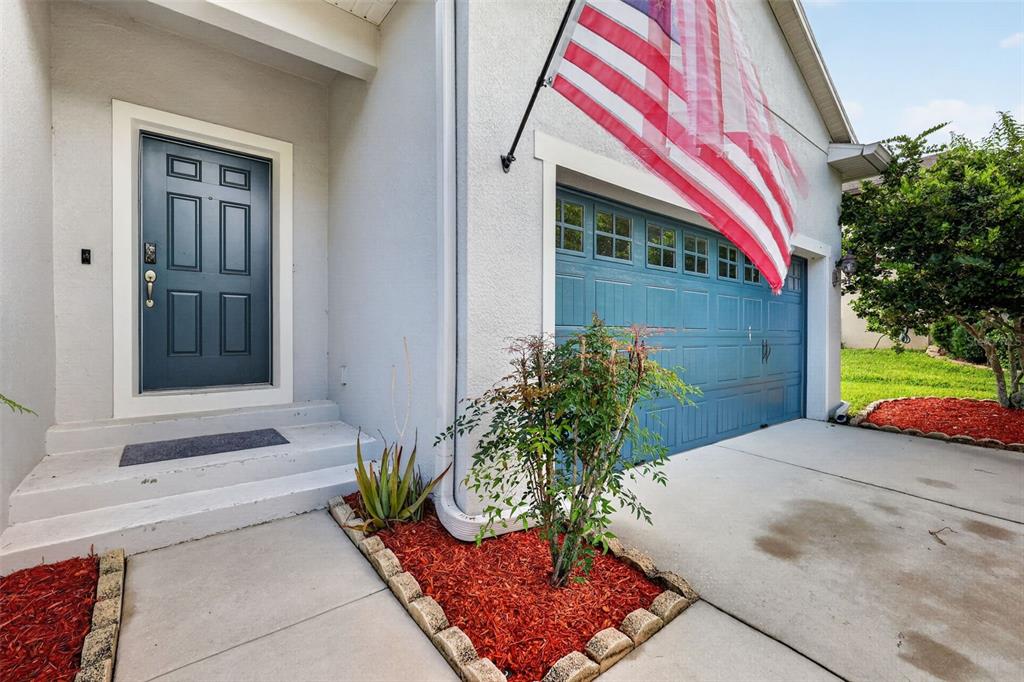 A front exterior view showing a blue garage door, a matching front door, and landscaping — 30115 CHEVAL STREET, MOUNT DORA, FL