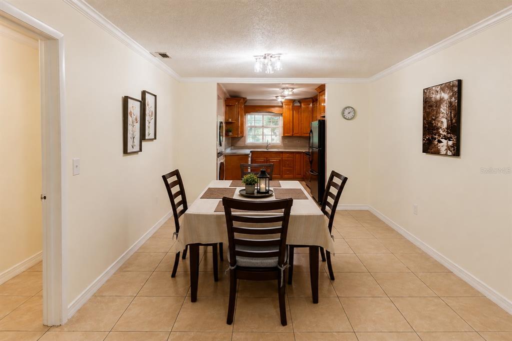 A dining area with a table and chairs leads into a kitchen with wood cabinets — 2305 HAYWOOD COURT UNIT 203, MAITLAND, FL