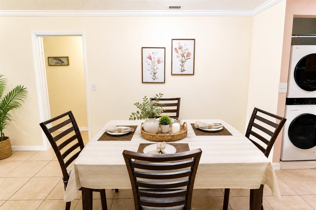 A dining area features a table with four chairs, floral wall art, and tiled flooring — 2305 HAYWOOD COURT UNIT 203, MAITLAND, FL