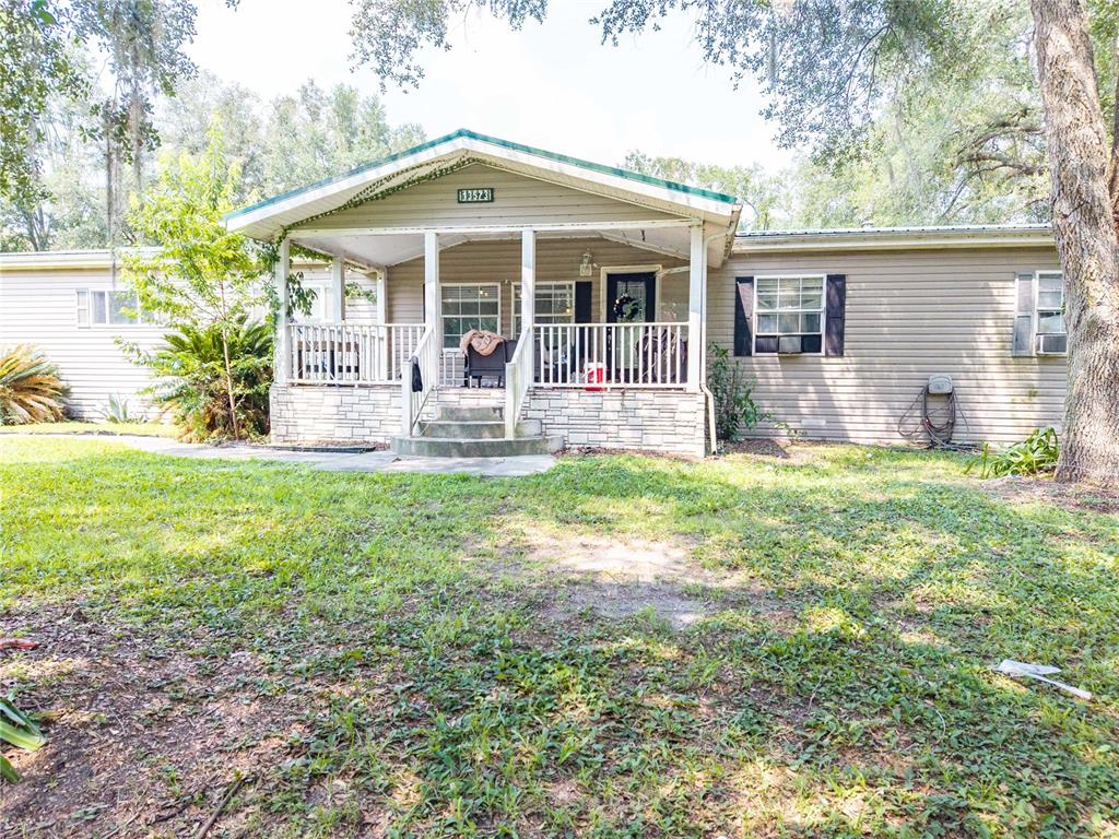 A single-story house with tan siding, a front porch, and a stone-accented foundation — 13573 98TH STREET, LIVE OAK, FL