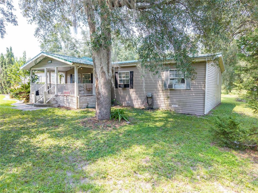 A single-story house with tan siding, a covered front porch, and a metal roof — 13573 98TH STREET, LIVE OAK, FL