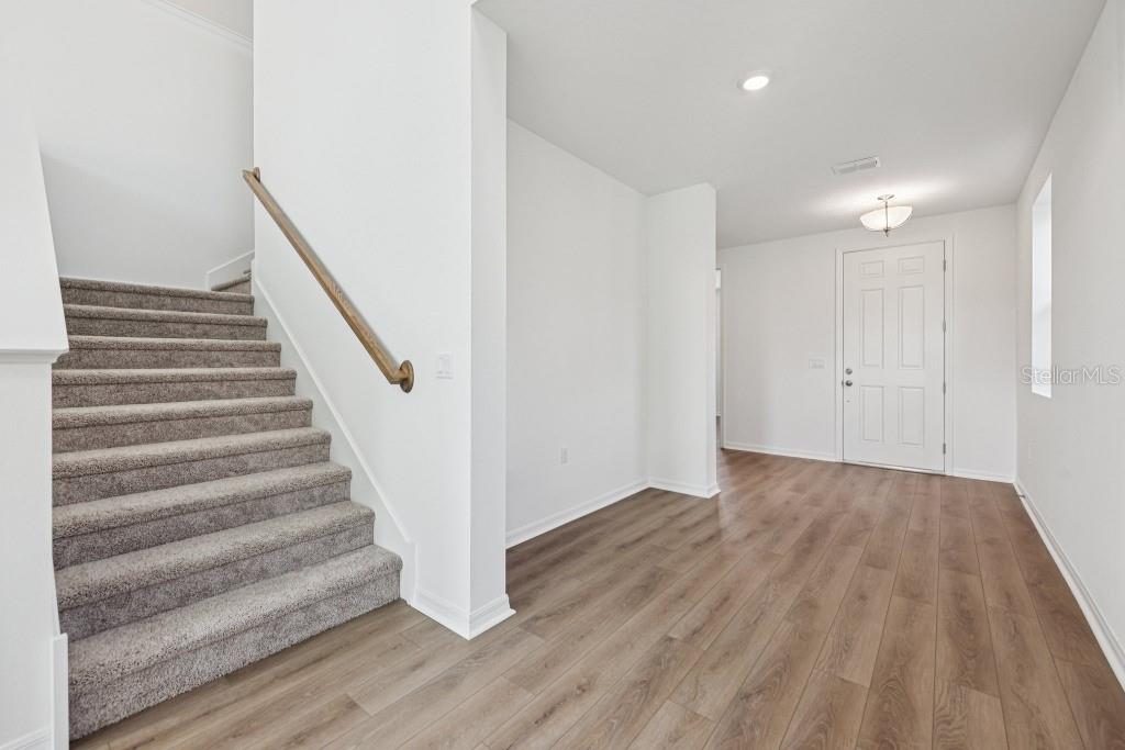An entryway features wood-look flooring, a carpeted staircase with a wooden handrail, and a door — 17631 LAKE STAR ROAD, WINTER GARDEN, FL