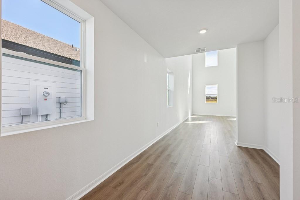 A long, narrow room with white walls, light wood-look flooring, and multiple windows — 17631 LAKE STAR ROAD, WINTER GARDEN, FL