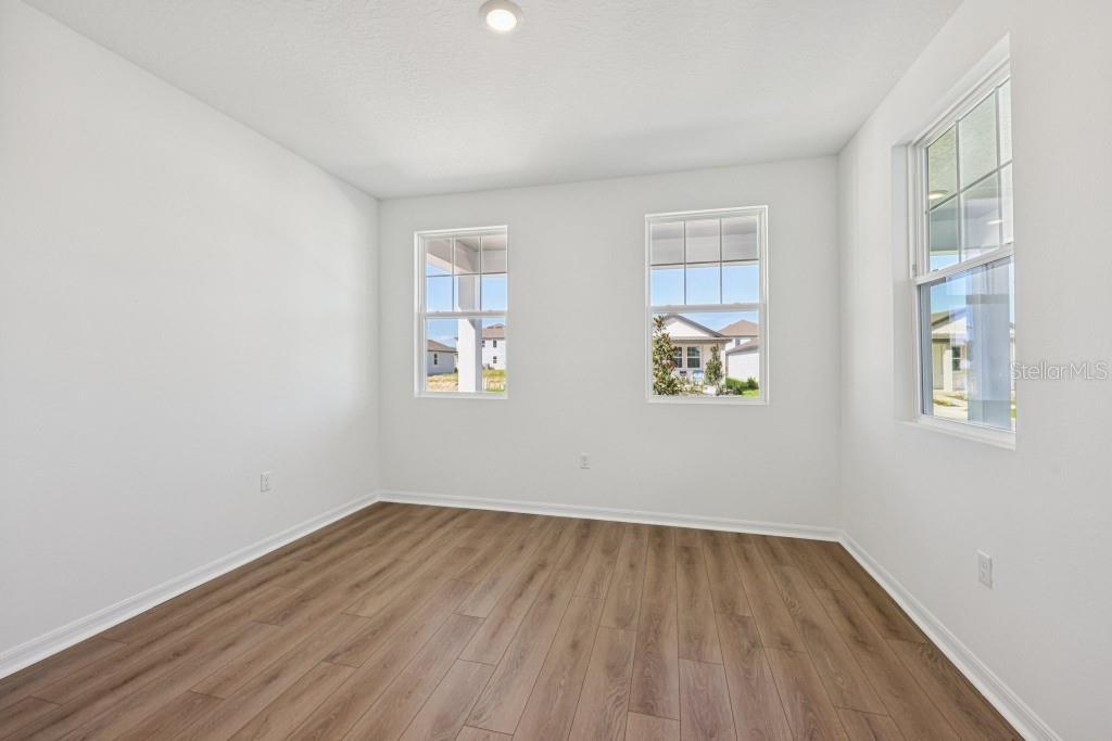 An empty room with white walls, wood-look flooring, and three windows — 17631 LAKE STAR ROAD, WINTER GARDEN, FL