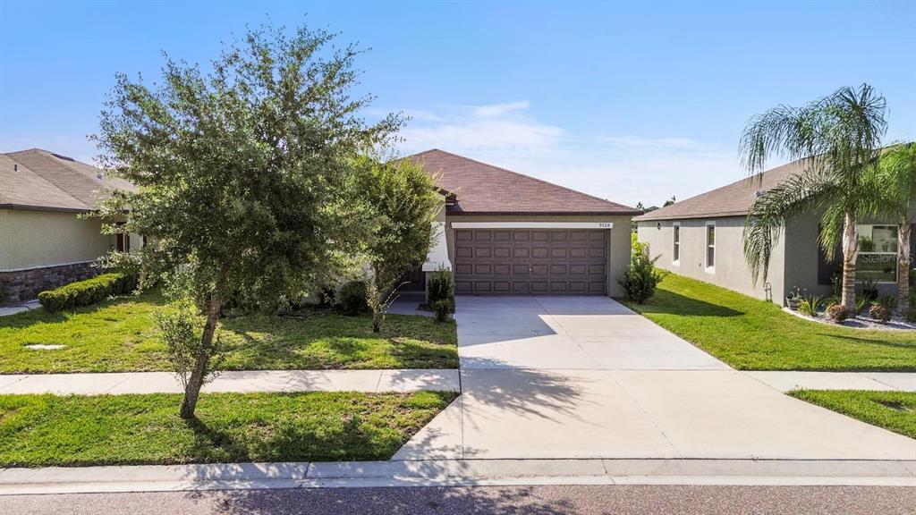 A single-story suburban house with a brown roof, a two-car garage, and a concrete driveway — 9728 CHANNING HILL DRIVE, RUSKIN, FL