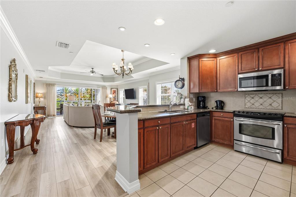 A hallway with tiled flooring and framed art leads toward a living area and bedroom — 7613 CABANA COURT UNIT 304, KISSIMMEE, FL