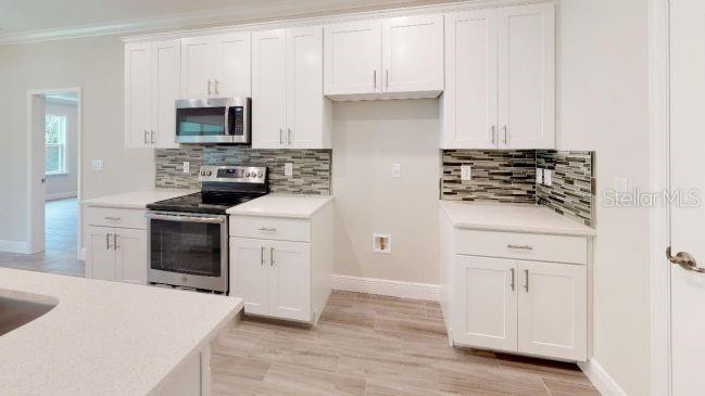 A kitchen with white cabinets, stainless steel appliances, a tiled backsplash, and light countertops — TBD MOHAWK ROAD, VENICE, FL