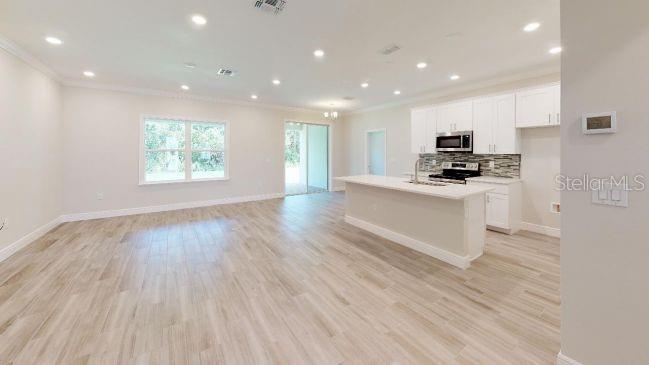 An open-concept kitchen and living area featuring light wood-look tile flooring and white cabinetry — TBD MOHAWK ROAD, VENICE, FL