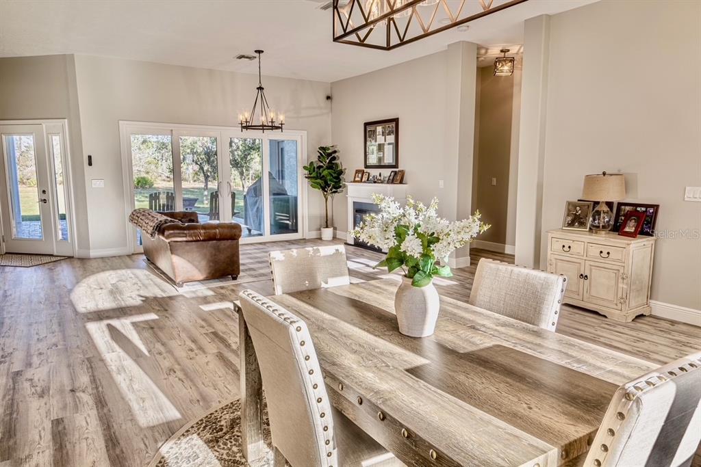 An open-concept living and dining area features wood-look flooring, a coffered ceiling, and white cabinetry — 7425 245TH STREET E, MYAKKA CITY, FL