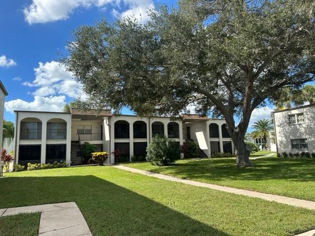 A two-story apartment building with arched balconies stands behind a large tree and lawn — 7701 STARKEY ROAD UNIT 731, SEMINOLE, FL