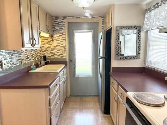 A kitchen features light wood cabinets, dark countertops, a tiled backsplash, and a glass-paneled door — 7701 STARKEY ROAD UNIT 731, SEMINOLE, FL
