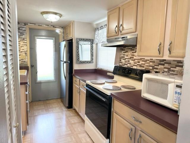 A kitchen features light wood cabinets, a stainless steel refrigerator, and a tiled backsplash — 7701 STARKEY ROAD UNIT 731, SEMINOLE, FL