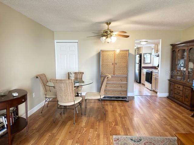 A dining room features a glass table with wicker chairs, a wooden hutch, and hardwood floors — 7701 STARKEY ROAD UNIT 731, SEMINOLE, FL
