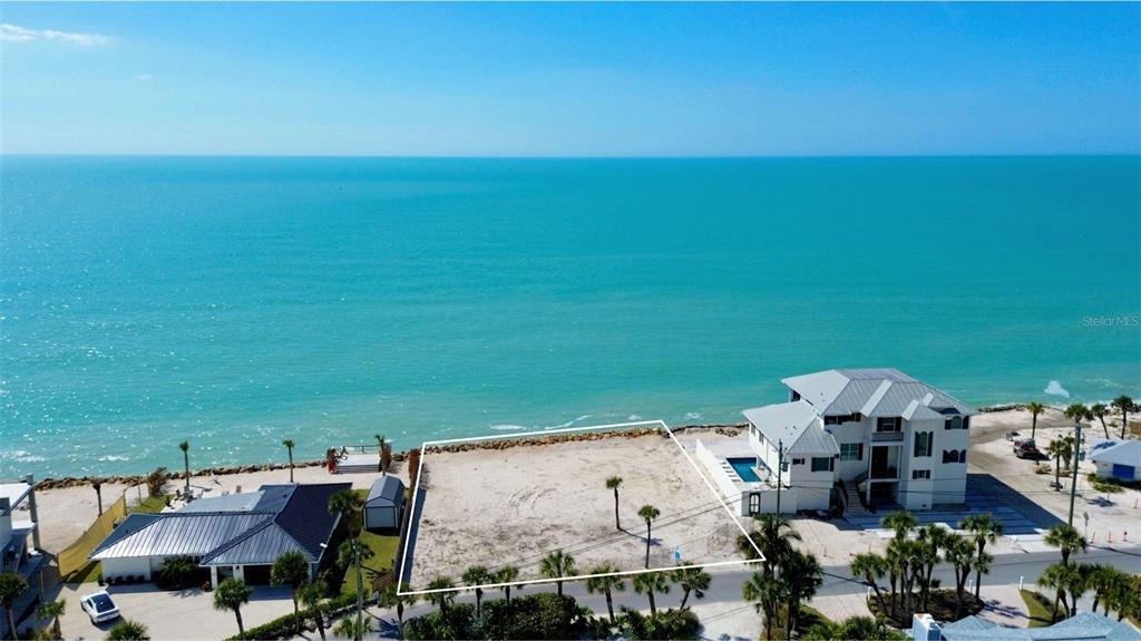 An aerial view shows a vacant beachfront lot situated between two houses along the coast — 3761 CASEY KEY ROAD, NOKOMIS, FL