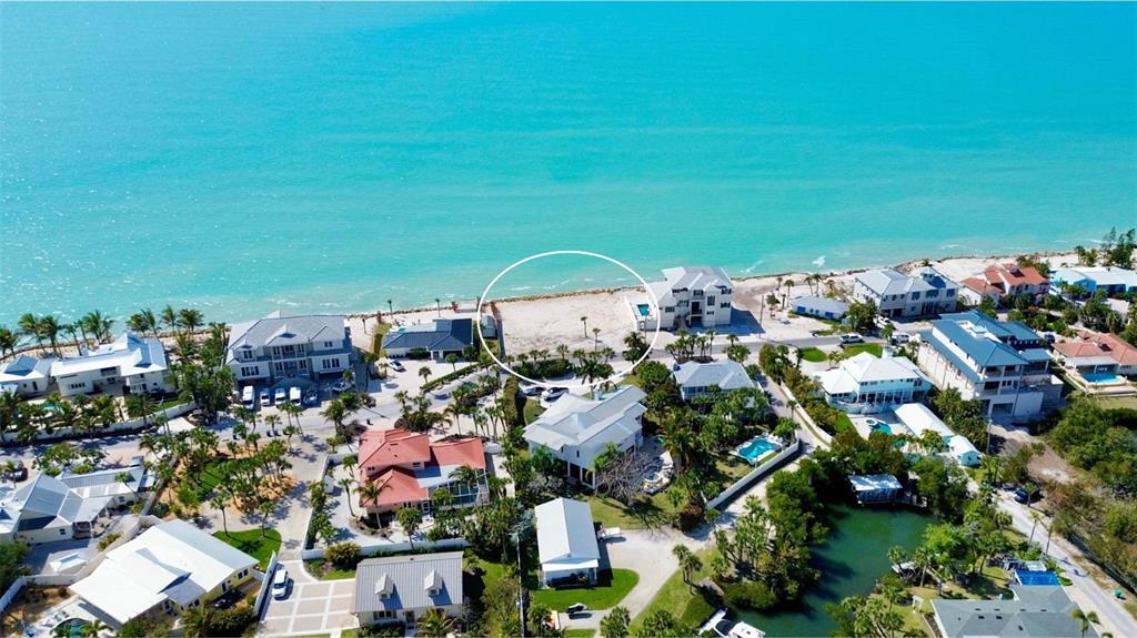 An aerial view shows a vacant beachfront lot circled among several coastal residential homes — 3761 CASEY KEY ROAD, NOKOMIS, FL