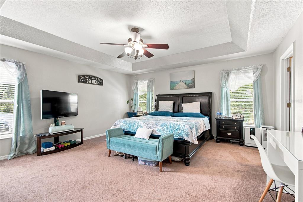 A bedroom features a tray ceiling, a dark wood bed frame, and a teal bench — 2340 SPRING HOLLOW LOOP, WESLEY CHAPEL, FL