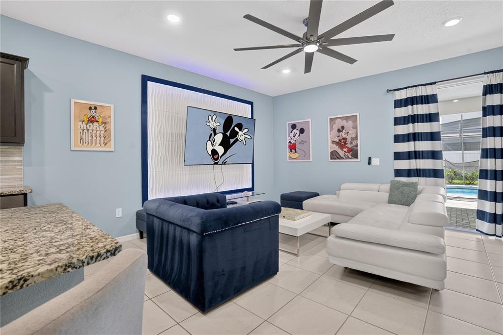 A living room features light blue walls, a Mickey Mouse theme, a white sectional, and tile flooring — 2127 LELANI CIRCLE, DAVENPORT, FL