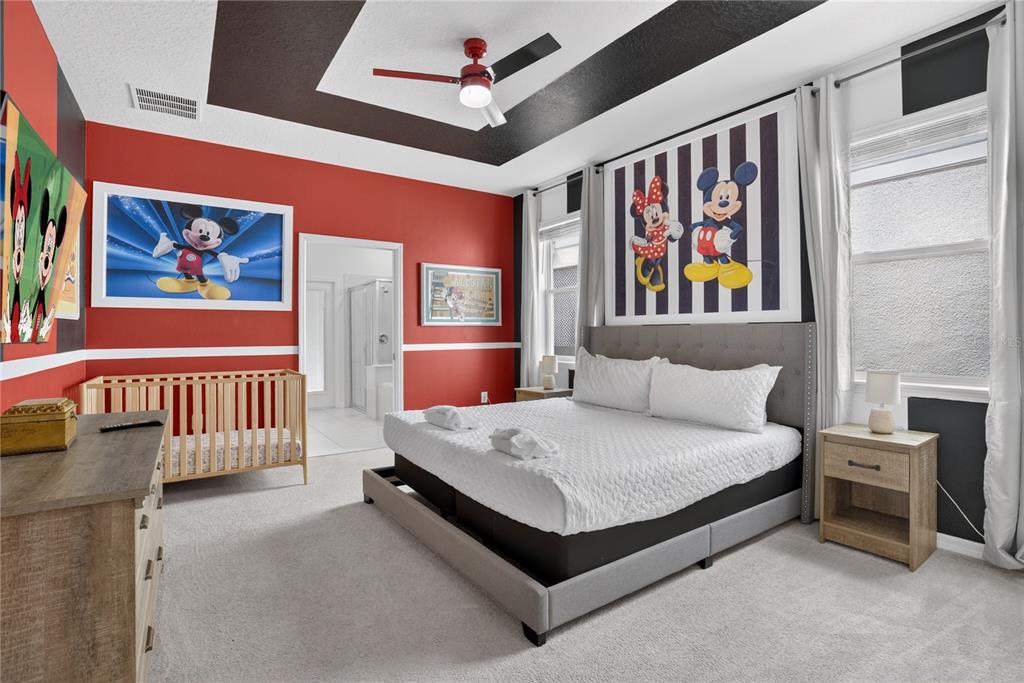 A bedroom features a king bed, a wooden crib, and Disney-themed wall art and decor — 2127 LELANI CIRCLE, DAVENPORT, FL