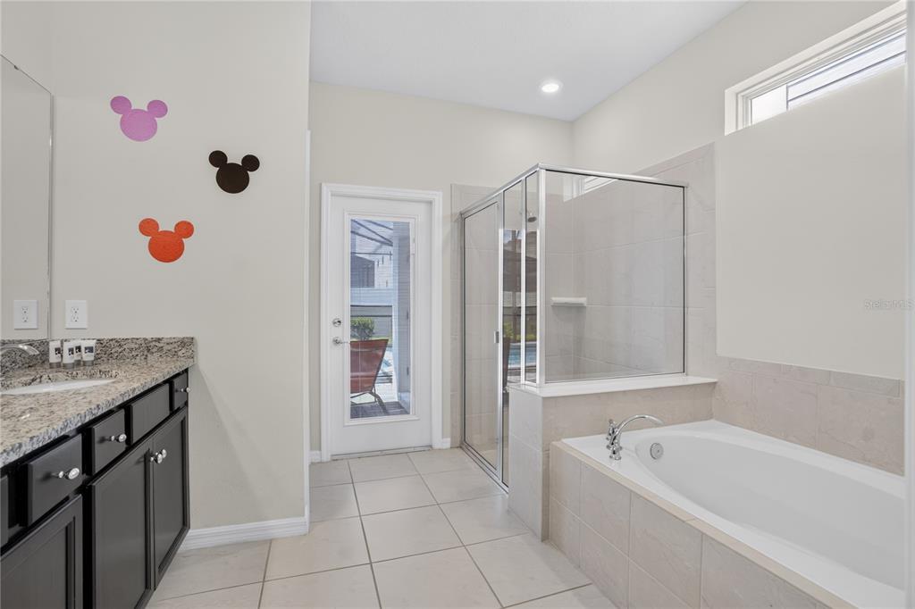 A bathroom features a vanity, a glass-enclosed shower, a soaking tub, and a glass door — 2127 LELANI CIRCLE, DAVENPORT, FL