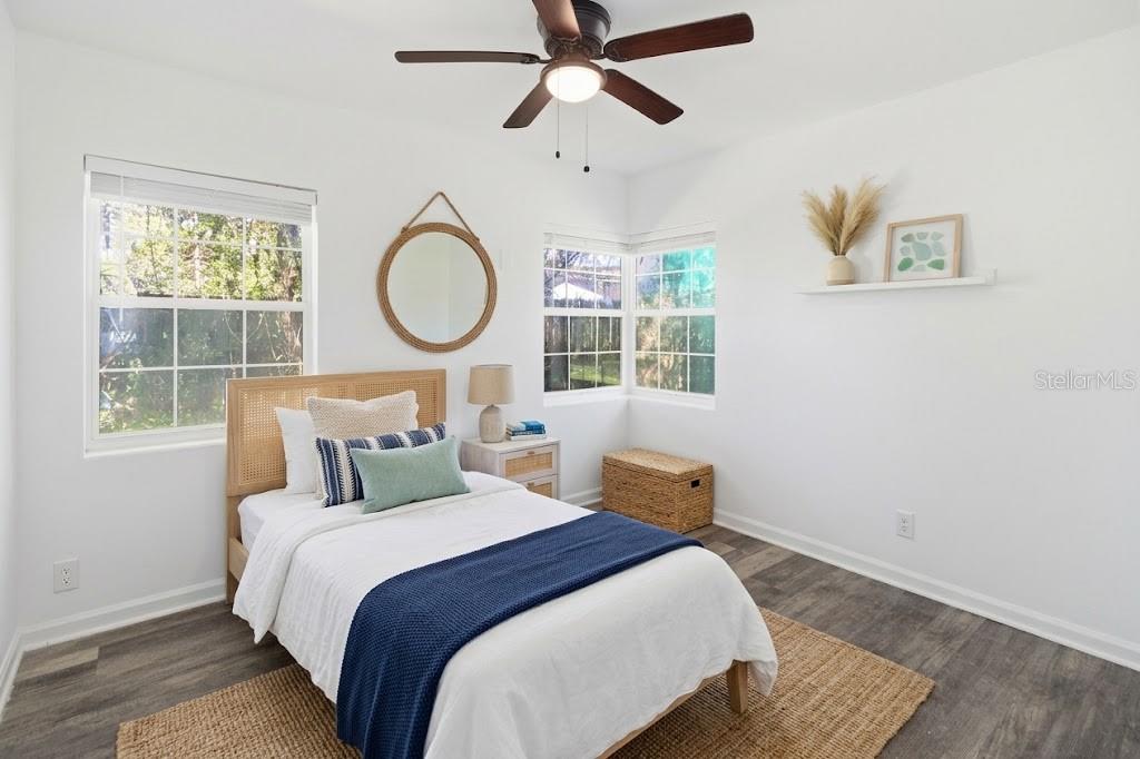 A bedroom features a bed with a rattan headboard, a ceiling fan, and white walls — 5405 WINDERMERE DRIVE, JACKSONVILLE, FL