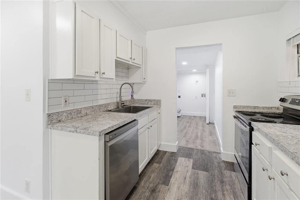 A kitchen with white cabinets, granite countertops, stainless steel appliances, and gray wood-look flooring — 5405 WINDERMERE DRIVE, JACKSONVILLE, FL