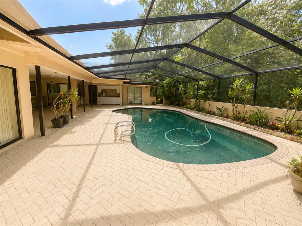 A screened-in patio features a swimming pool, brick paver decking, and an outdoor kitchen area — 6701 PEMBERTON VIEW DRIVE, SEFFNER, FL